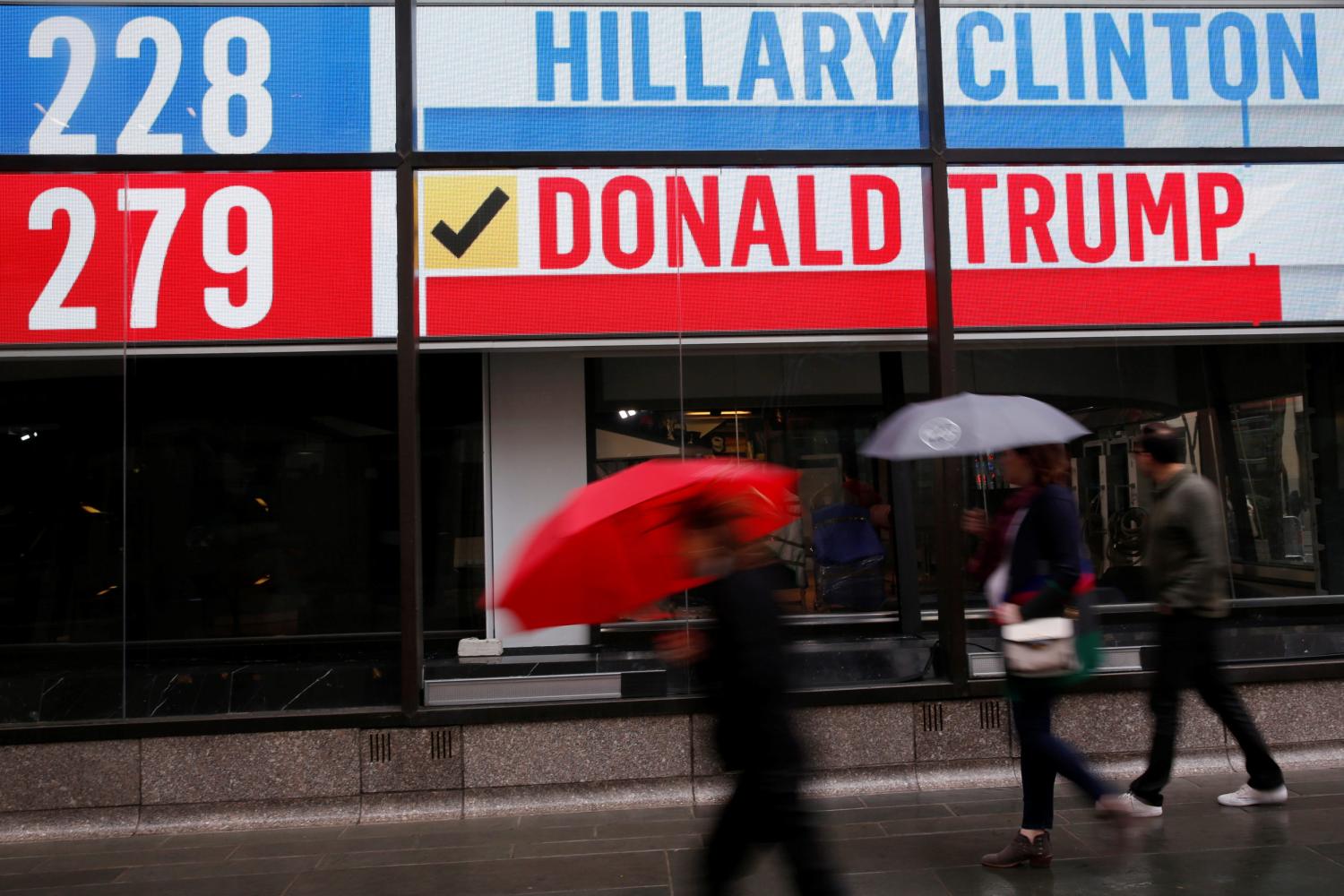 People walk by an electronic billboard in New York U.S.