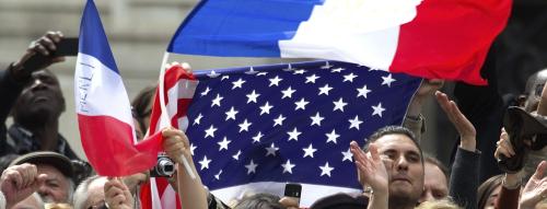 People with French and American flags react as outgoing French President Nicolas Sarkozy (not pictured) attends a ceremony at the Tomb of the Unknown Soldier at the Arc de Triomphe to commemorate the end of World War II in Paris May 8, 2012. REUTERS/Charles Platiau (FRANCE - Tags: POLITICS CONFLICT)