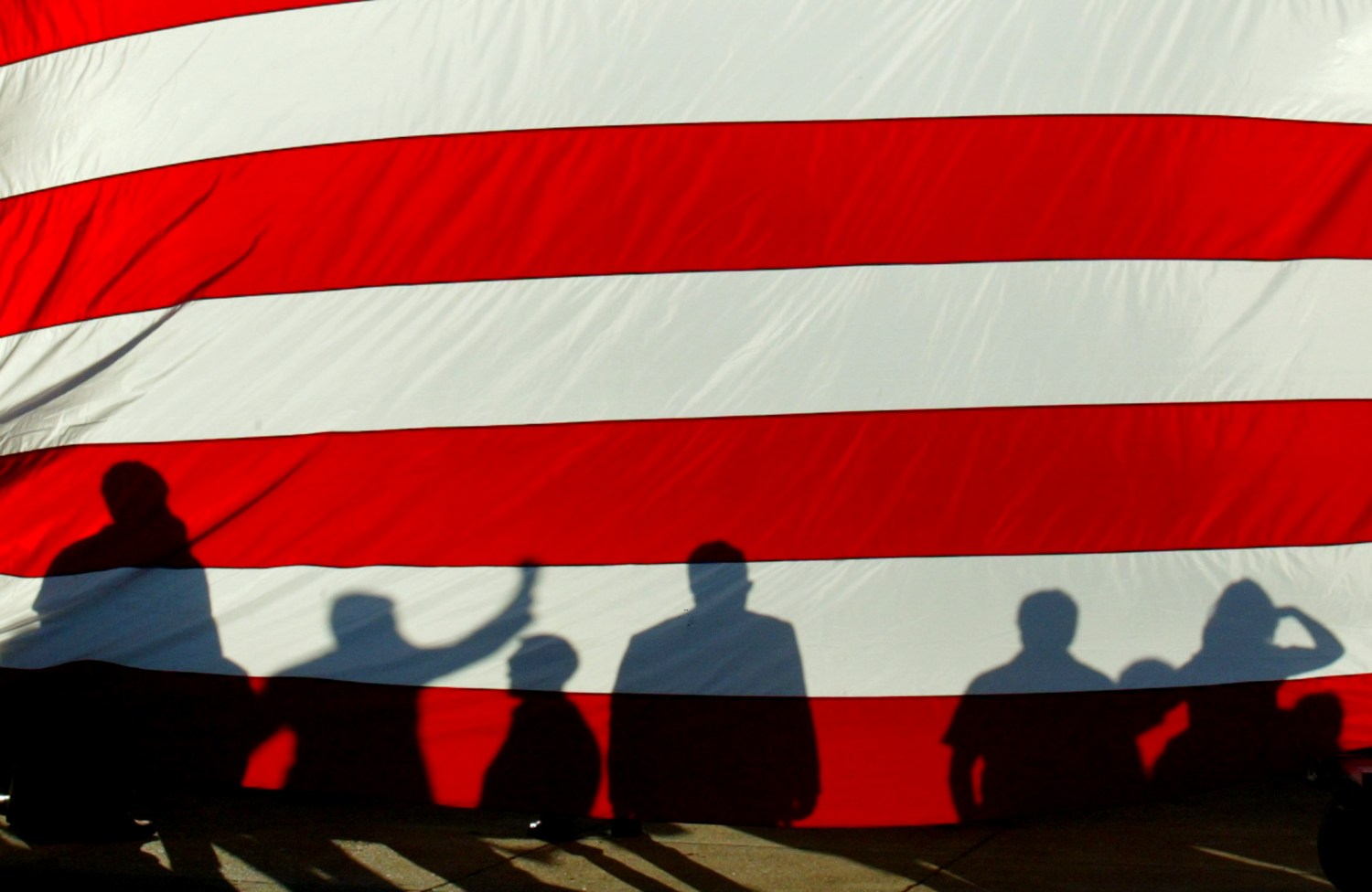 The stripes on the American flag overlaid with shadows cast by campaigners onstage.