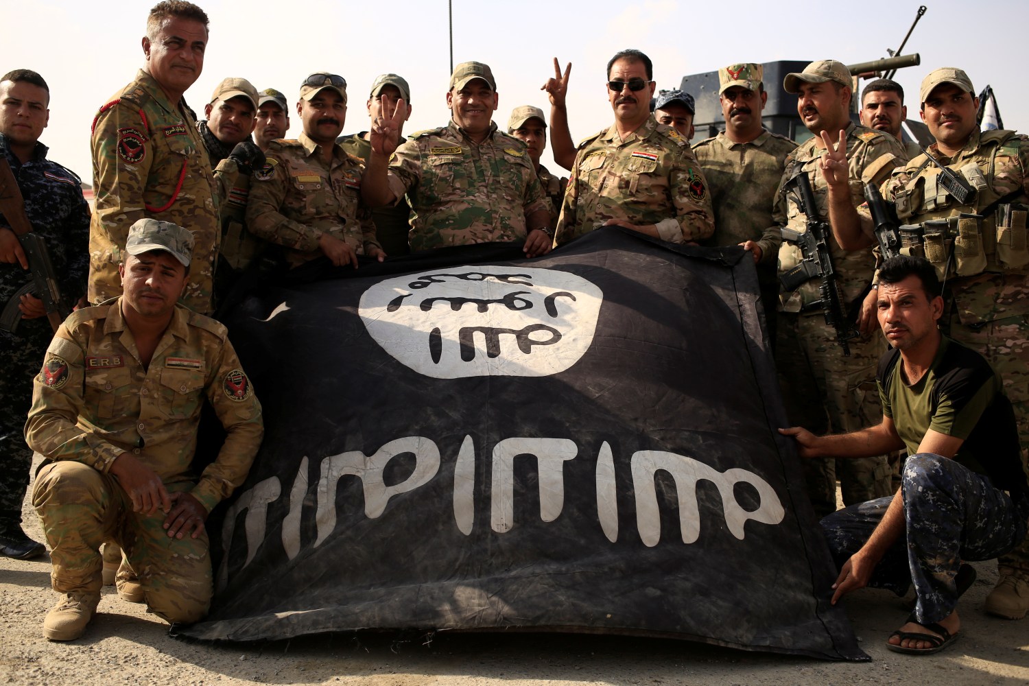 Iraqi soldiers celebrate as they pose with the Islamic State flag along a street of the town of al-Shura, which was recaptured from Islamic State (IS) on Saturday, south of Mosul, Iraq October 30, 2016. REUTERS/Zohra Bensemra - RTX2R34S