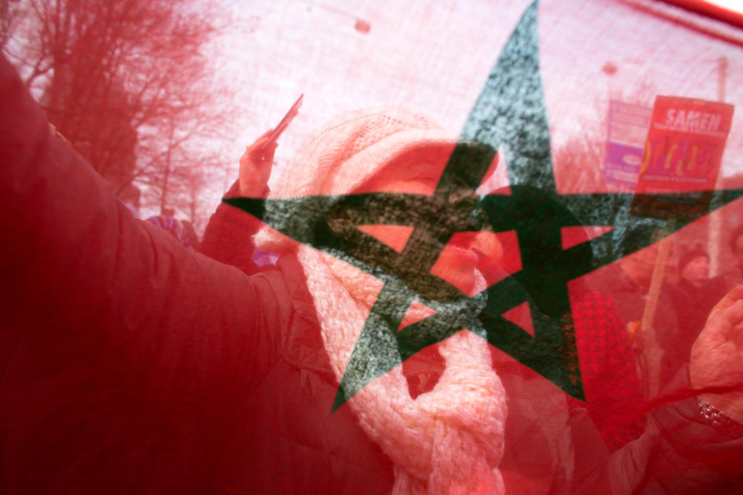 A protester is pictured through a Moroccan national flag.