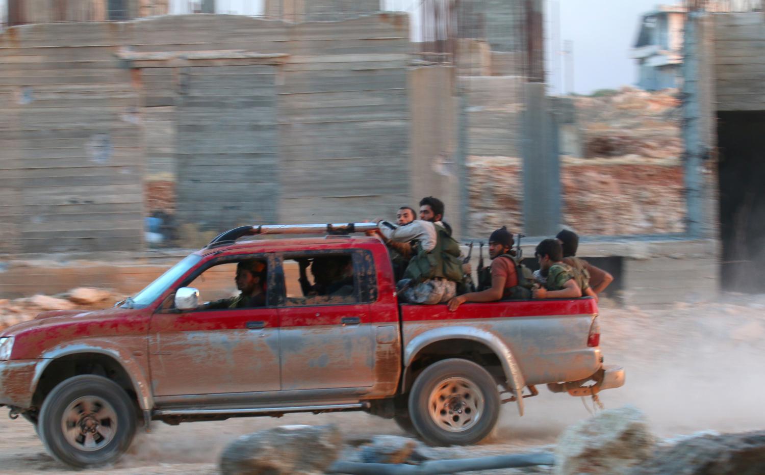 Fighters of the Syrian Islamist rebel group Jabhat Fateh al-Sham, the former al Qaeda-affiliated Nusra Front, ride on a pick-up truck in the 1070 Apartment Project area in southwestern Aleppo, Syria August 5, 2016. REUTERS/Ammar Abdullah - RTSL8ZO