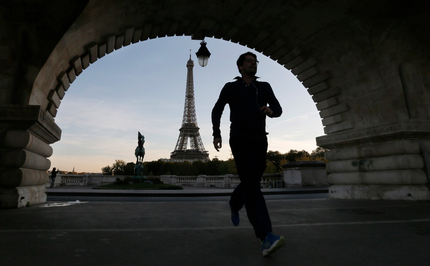 A jogger takes an early morning run on bridge near the Eiffel Tower in Paris.