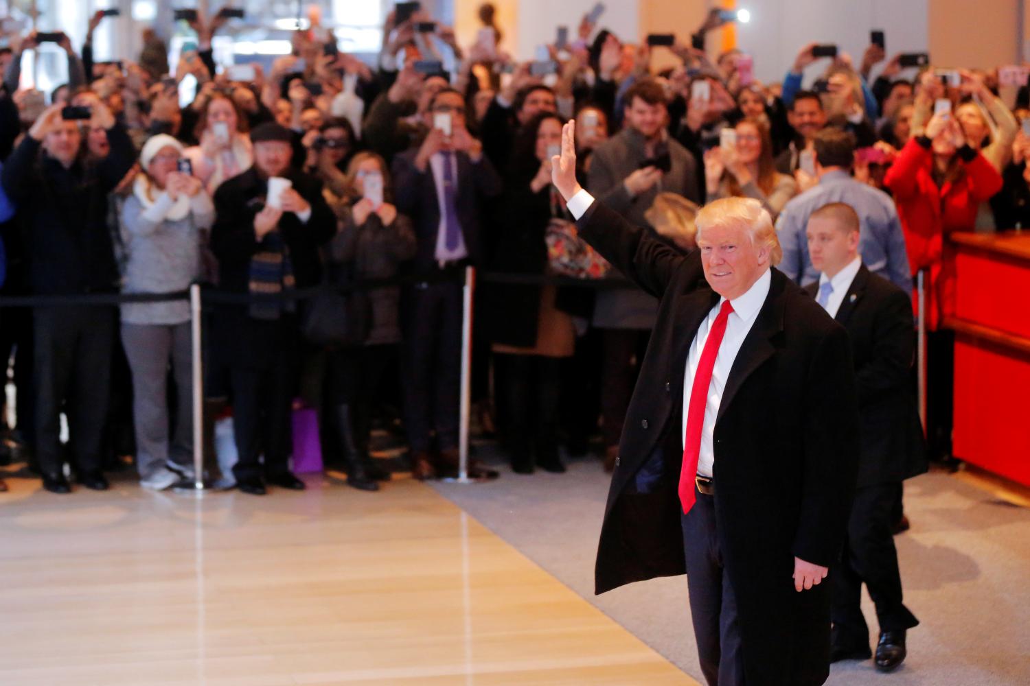 U.S. President elect Donald Trump reacts to a crowd gathered in the lobby of the New York Times building after a meeting in New York