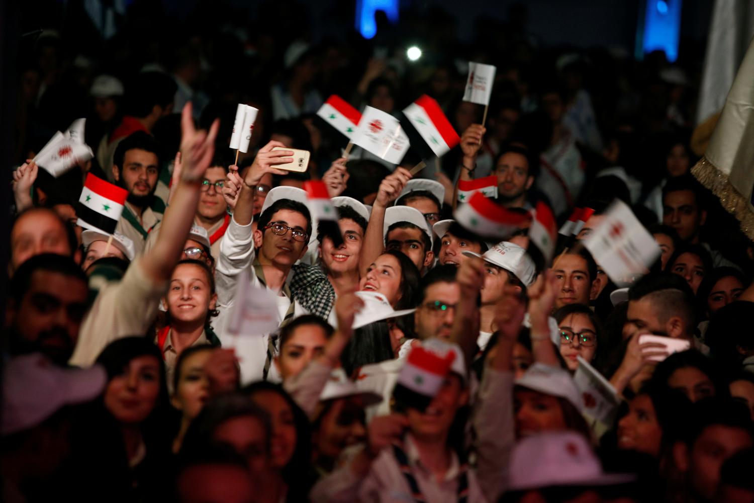 People carry Syrian national flags while they take a selfie as they attend a festival for peace organized by Caritas in al-Zaytoun church in Old Damascus, Syria October 31, 2016. Picture taken October 31, 2016. REUTERS/Omar Sanadiki - RTX2RCWT