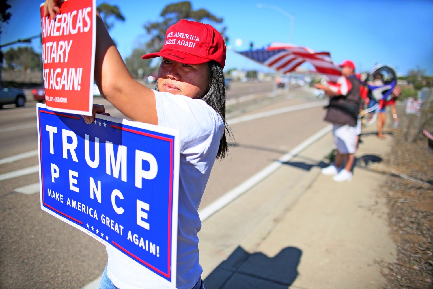 Demonstrator Ly Kou holds a sign along with others in support of President elect Donald Trump outside of Camp Pendleton in Oceanside, California U.S. November 11, 2016. REUTERS/Sandy Huffaker - RTX2TA8C