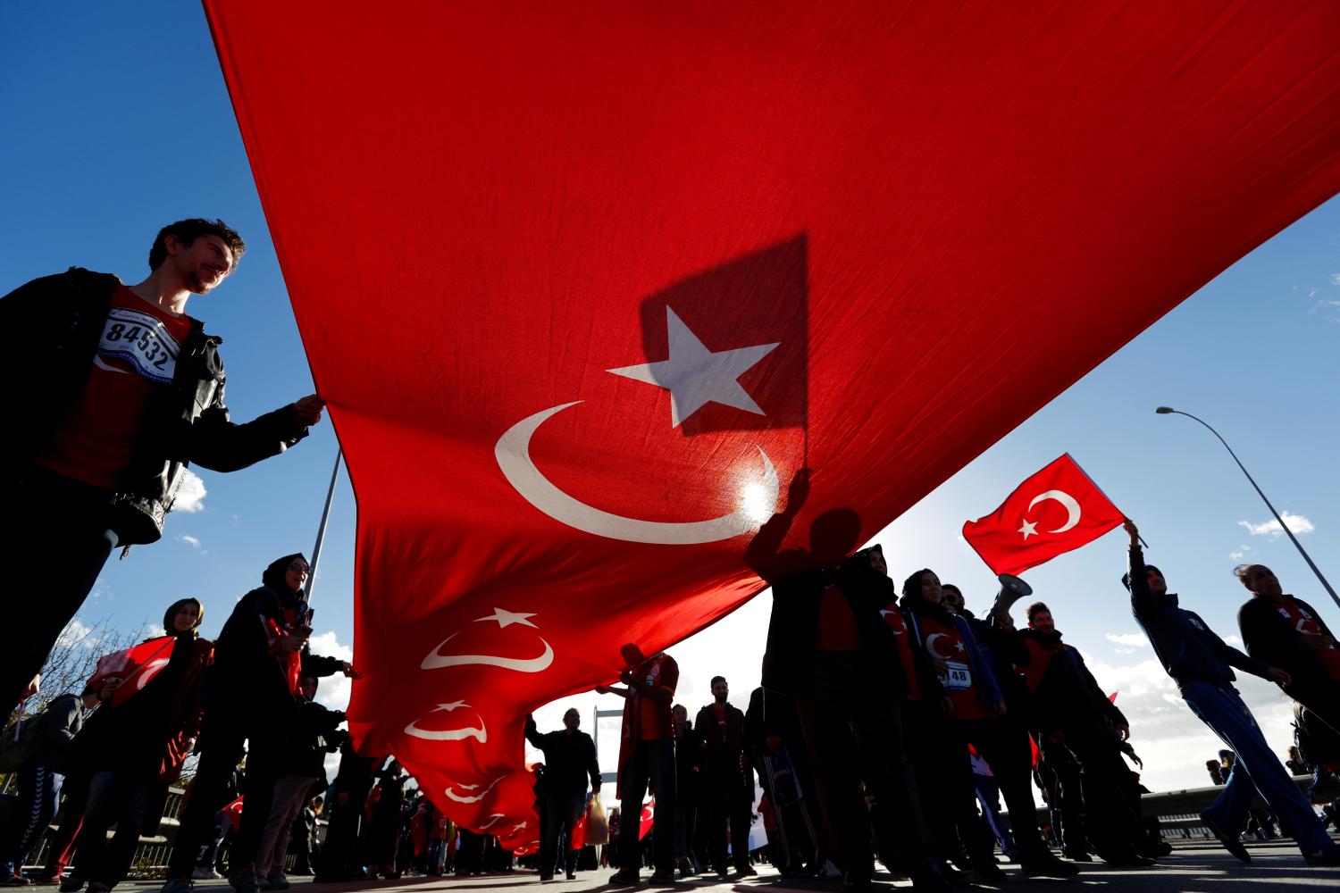People march with a huge Turkish flag on the July 15 Martyrs' Bridge, known as the Bosphorus Bridge, which links the city's European and Asian sides, during the 38th annual Istanbul Marathon in Istanbul, Turkey, November 13, 2016. REUTERS/Murad Sezer - RTX2TF57