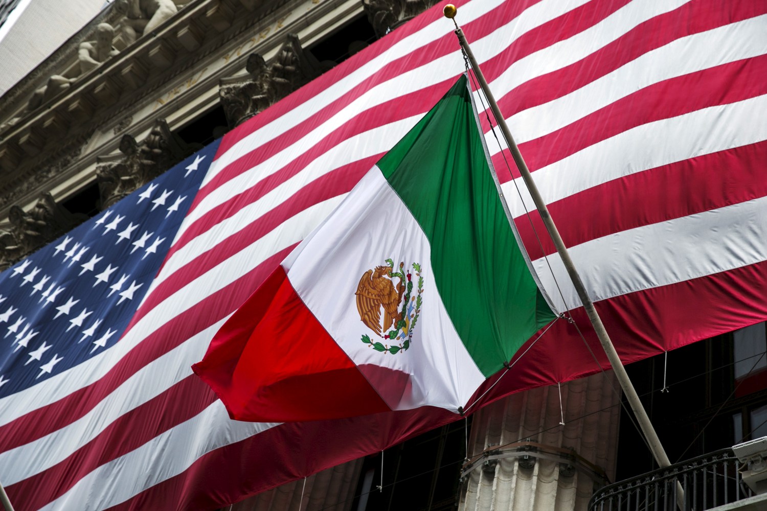 The flag of Mexico changes in front of a large U.S. flag in front of the New York Stock Exchange September 4, 2015. REUTERS/Lucas Jackson - RTX1R4GU