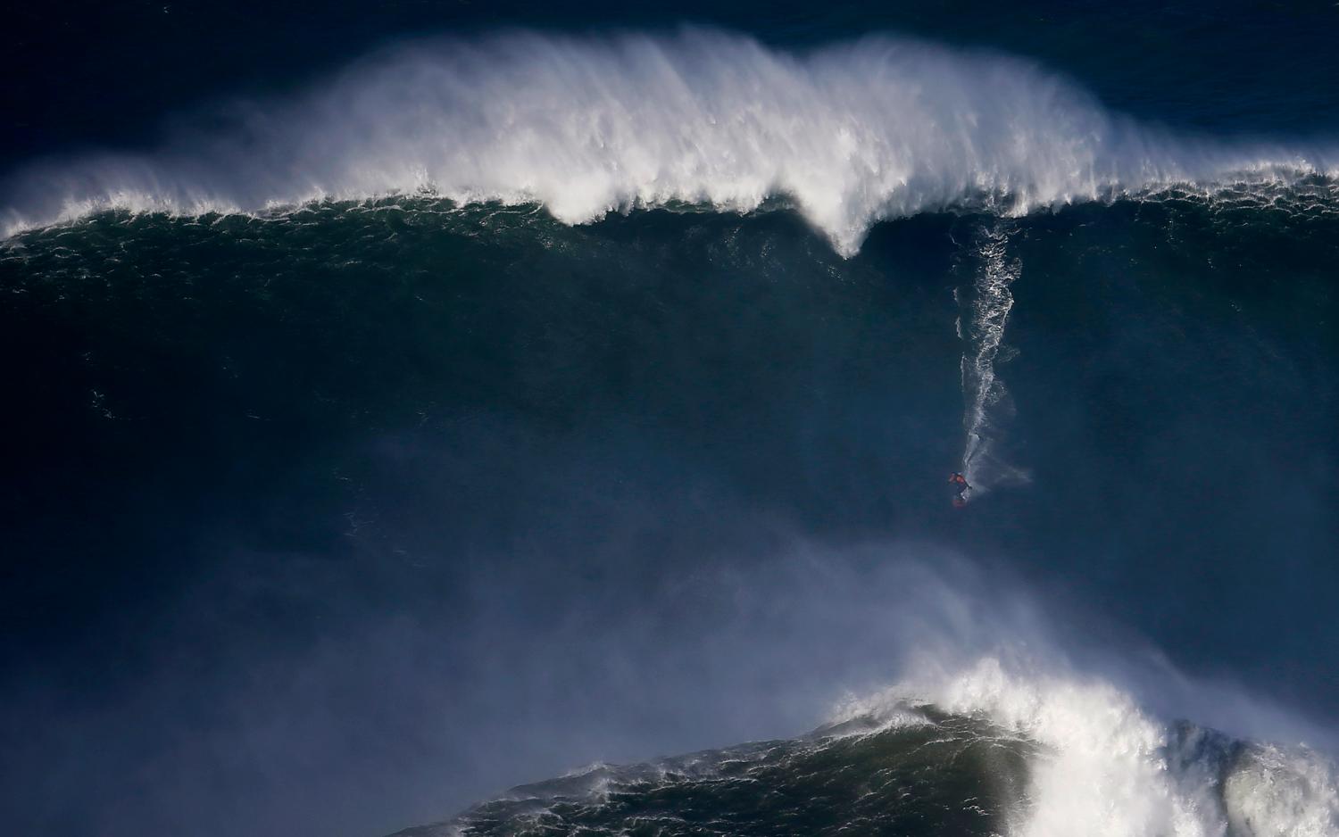 A surfer drops in on a large wave at Praia do Norte, in Nazare
