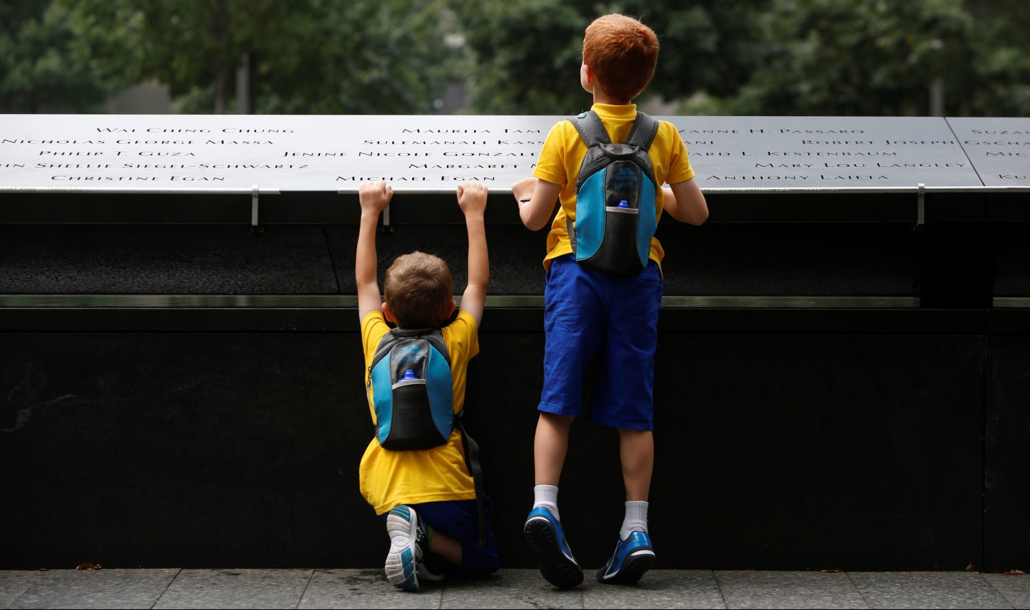 Children peer into the south reflecting pool at the National September 11 Memorial and Museum .