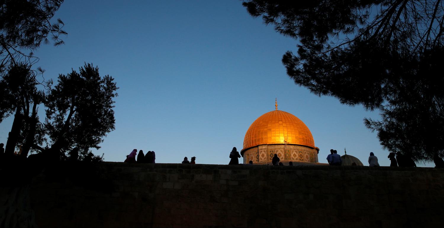 Palestinians are silhouetted as they walk in front of the Dome of the Rock on the compound known to Muslims as al-Haram al-Sharif and to Jews as Temple Mount in Jerusalem's Old City, before the start of morning prayers marking the first day of Eid al-Adha celebrations, early morning September 12, 2016. REUTERS/Ammar Awad - RTSNCVX