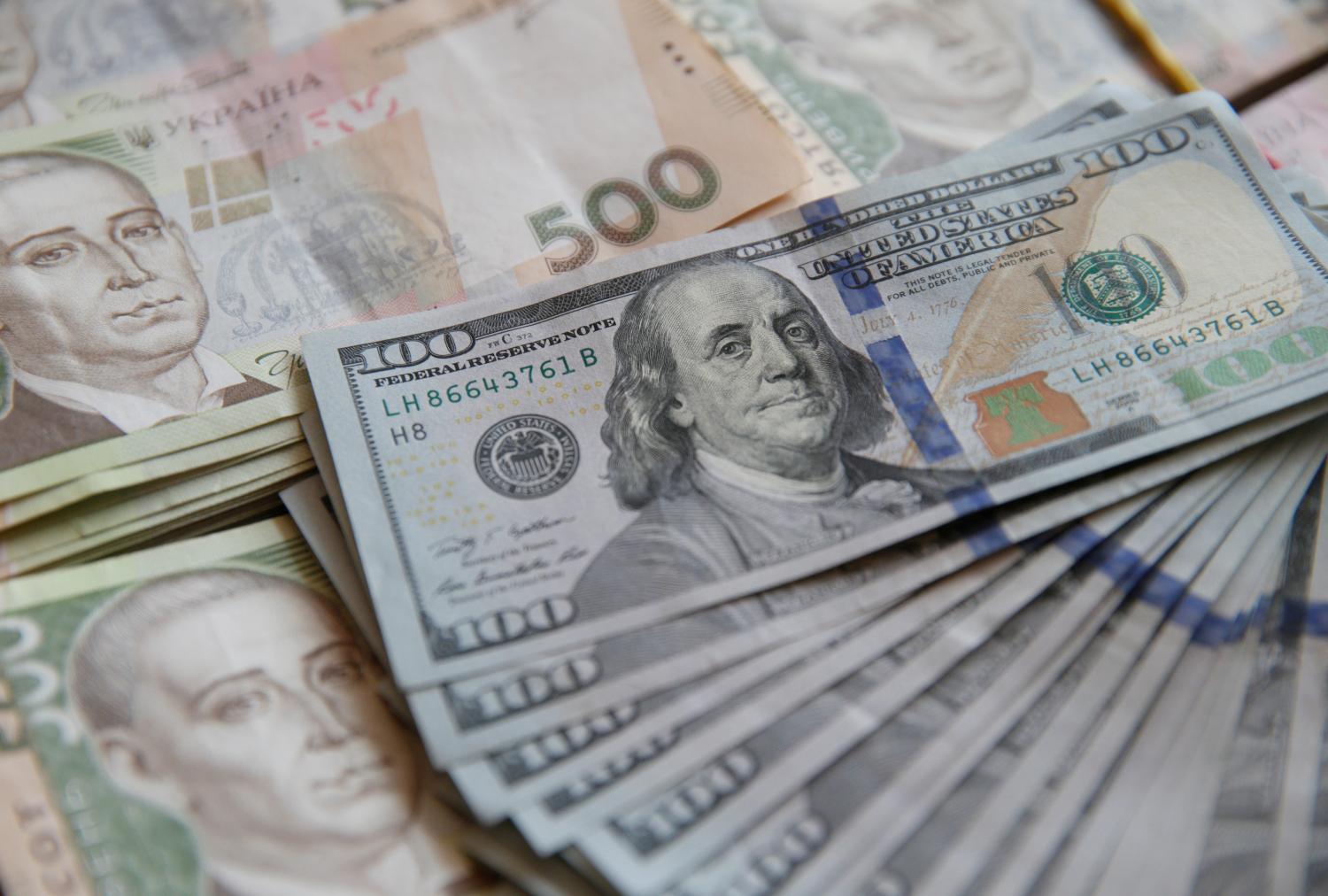 U.S. hundred dollar bills sit on top of Ukranian currency.