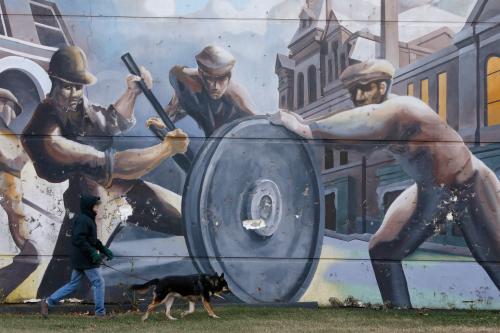 A man walks his dog past a mural depicting factory workers in Chicago.