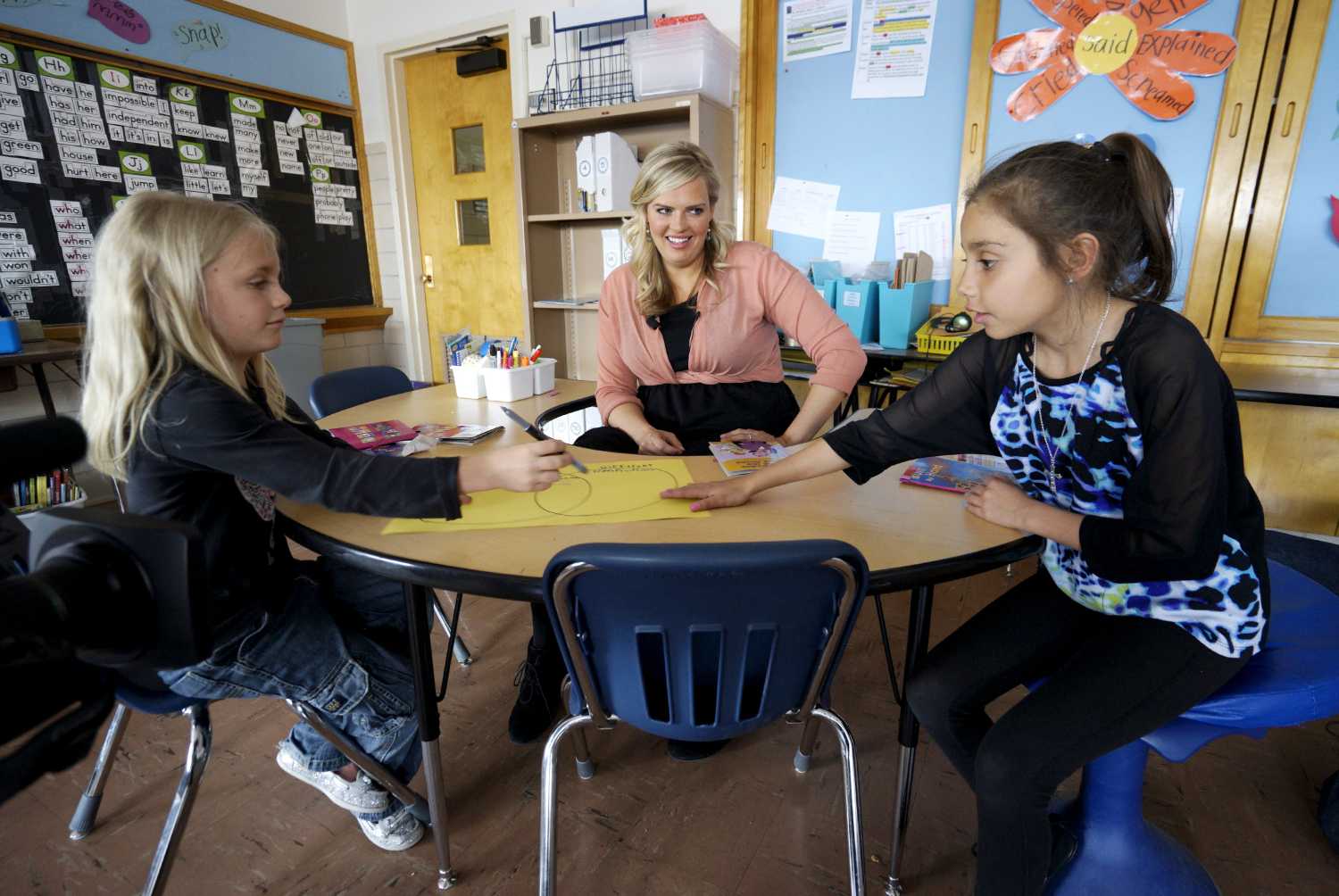 Kyle Schwartz (C), a 3rd grade teacher, works with students Mckylah Lenkiewicz (L) and Juliana Enquist in her classroom at Doull Elementary School in Denver