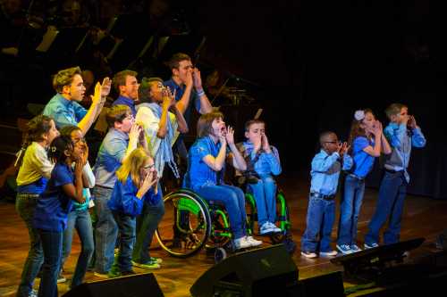 Children who have attended one of several camps for disabled children perform on stage