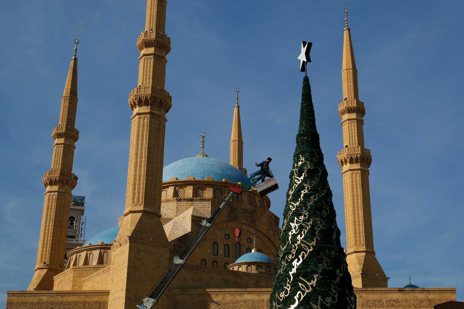 A worker decorates a Christmas tree designed by Lebanese designer Elie Saab in front of the Al-Amin mosque in Beirut, Lebanon, December 9, 2015. Picture taken December 9, 2015. REUTERS/Jamal Saidi - RTX1Y14M