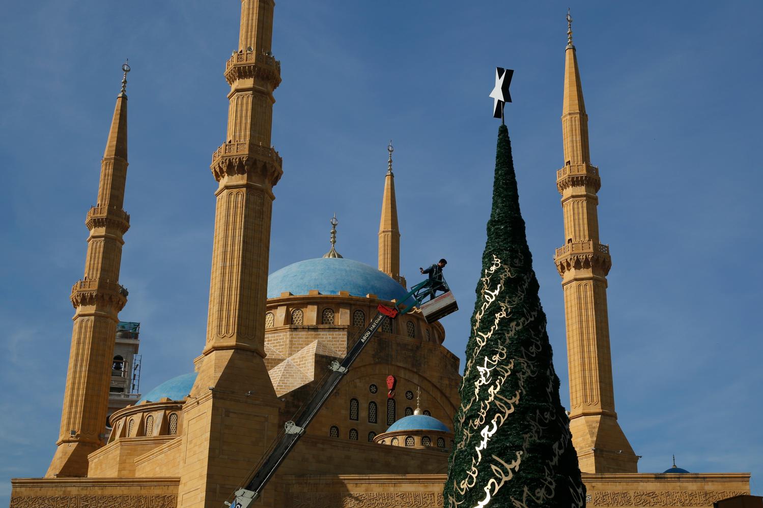 A worker decorates a Christmas tree designed by Lebanese designer Elie Saab in front of the Al-Amin mosque in Beirut, Lebanon, December 9, 2015. Picture taken December 9, 2015. REUTERS/Jamal Saidi - RTX1Y14M