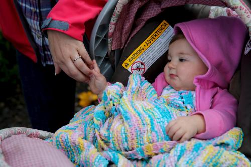 A woman walks with her baby in a stroller.