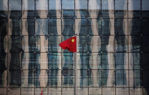 A Chinese national flag flutters at the headquarters of a commercial bank on a financial street near the headquarters of the People's Bank of China, China's central bank, in central Beijing November 24, 2014. REUTERS/Kim Kyung-Hoon/File Photo - RTSGATS