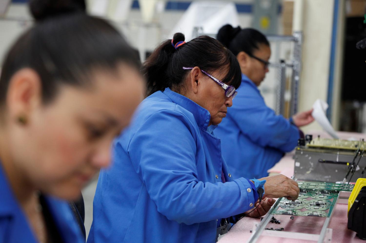 Employees work on a printed circuit board