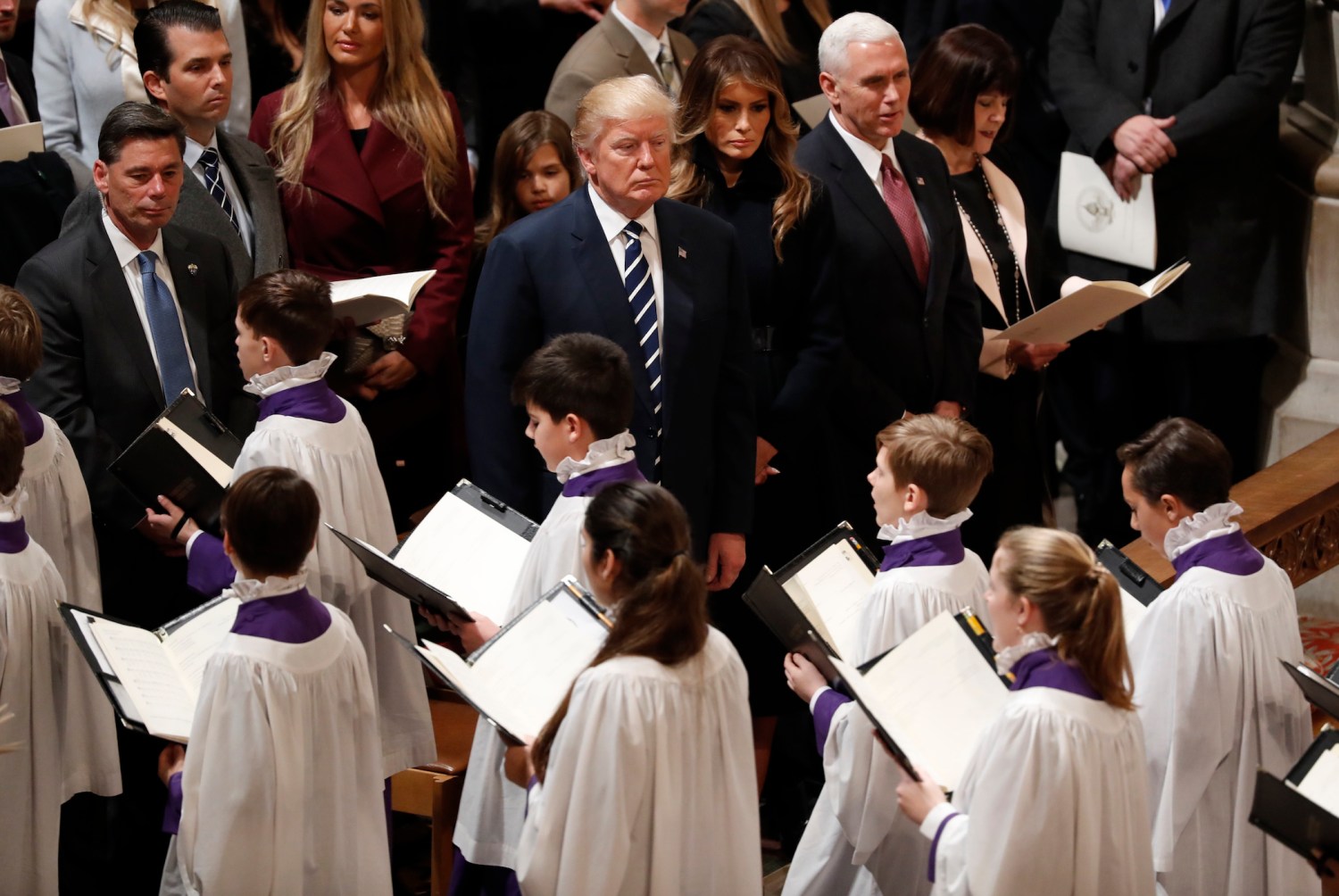 U.S. President Donald Trump (C) watches acolytes pass by as he is accompanied by his wife Melania, Vice President Mike Pence and his wife Karen (R), during a prayer service at Washington National Cathedral the morning after his inauguration, in Washington, U.S., January 21, 2017. REUTERS/Carlos Barria - RTSWPKT