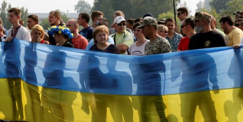 Pro-Ukrainian activists hold a national flag as they protest against a procession petitioning for peace organized by the Ukrainian Orthodox Church of the Moscow Patriarchate, in the city of Boryspil outside Kiev, Ukraine, July 25, 2016. REUTERS/Valentyn Ogirenko - RTSJKHH