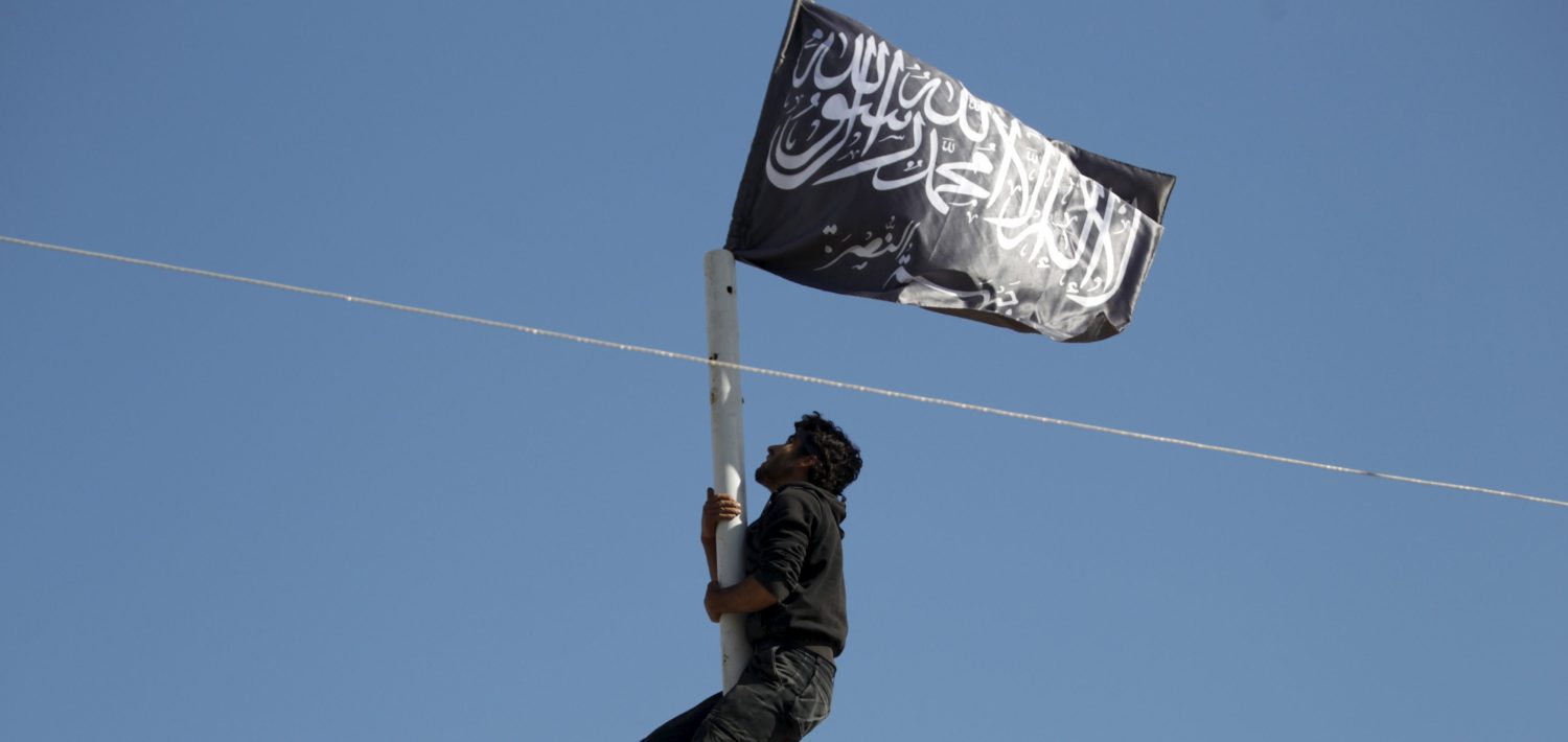 A member of al Qaeda's Nusra Front climbs a pole where a Nusra flag was raised at a central square in the northwestern city of Ariha, after a coalition of insurgent groups seized the area in Idlib province May 29, 2015. A Syrian insurgent alliance which has captured the last government-held town in the northwestern Idlib province made further advances on Friday, a monitoring group and fighters said. REUTERS/Khalil Ashawi - RTR4Y10S