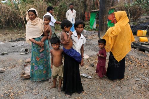 A family stands beside remains of a market which was set on fire, in Rohingya village outside Maungdaw, in Rakhine state, Myanmar October 27, 2016. Picture taken October 27, 2016. REUTERS/Soe Zeya Tun - RTX2TZUH