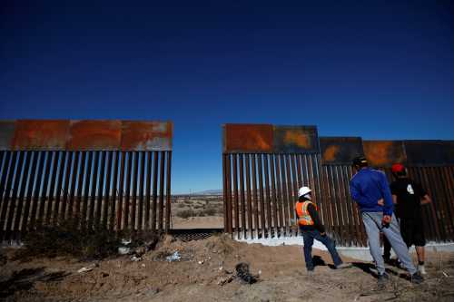 A worker chats with residents at a newly built section of the U.S.-Mexico border fence at Sunland Park, U.S. opposite the Mexican border city of Ciudad Juarez, Mexico January 26, 2017. REUTERS/Jose Luis Gonzalez - RTSXKER