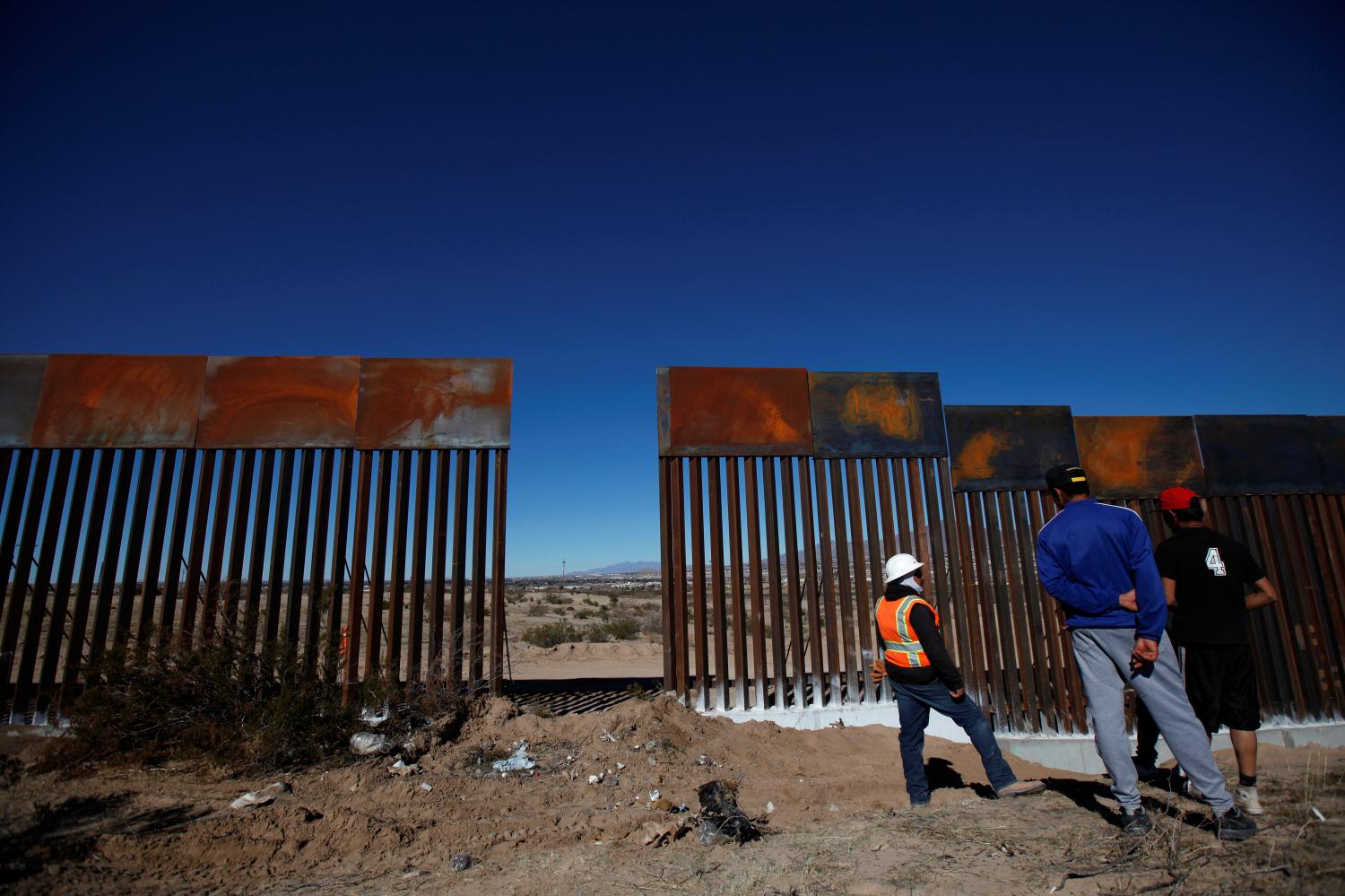 A worker chats with residents at a newly built section of the U.S.-Mexico border fence at Sunland Park, U.S. opposite the Mexican border city of Ciudad Juarez, Mexico January 26, 2017. REUTERS/Jose Luis Gonzalez - RTSXKER