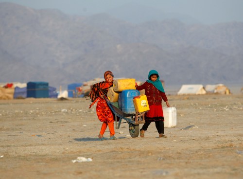 Afghan refugee girls carry drinking water in containers at a refugee camp on the outskirts of Jalalabad, Afghanistan, February 12, 2017. Picture taken February 12, 2017. REUTERS/Parwiz - RTSYEKZ