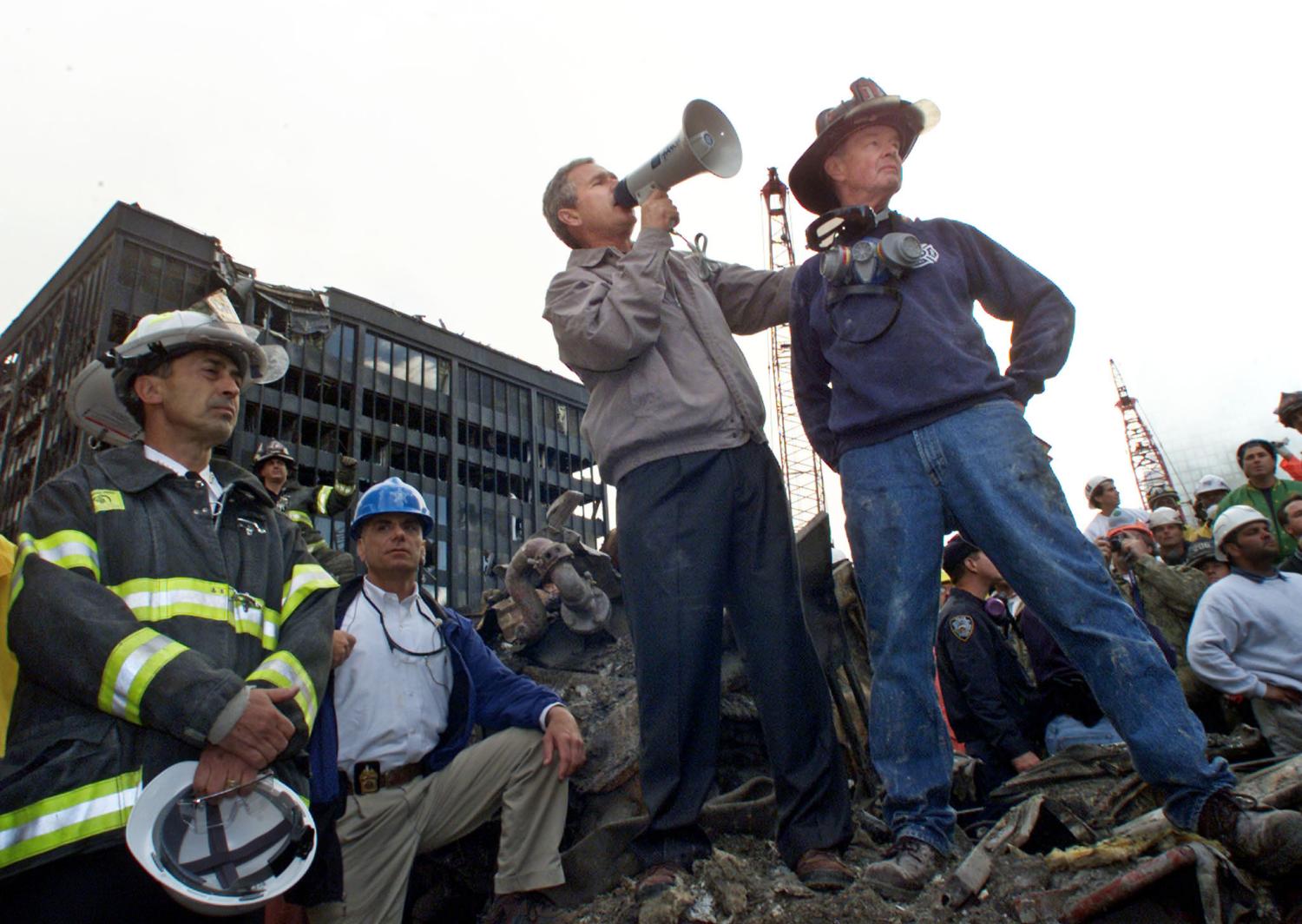 U.S. President George W. Bush addresses a crowd as he stands with retired firefighter Bob Beckwith (R) from Ladder 117 at the scene of the World Trade Center disaster in New York, September 14, 2001. The World Trade Center Towers and 7 World Trade Center were destroyed after both the landmark towers were struck by two hijacked planes in a terror attack on September 11. REUTERS/Win McNamee SB/SV - RTRMRTX