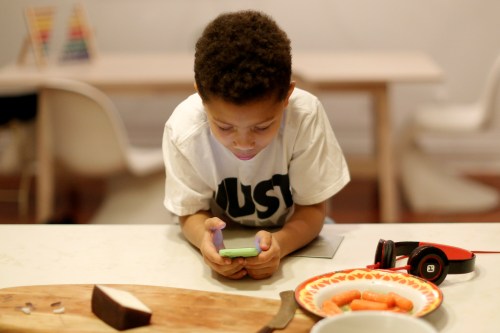 Penelope Ghartey plays a game on his phone at his home in Brooklyn, New York