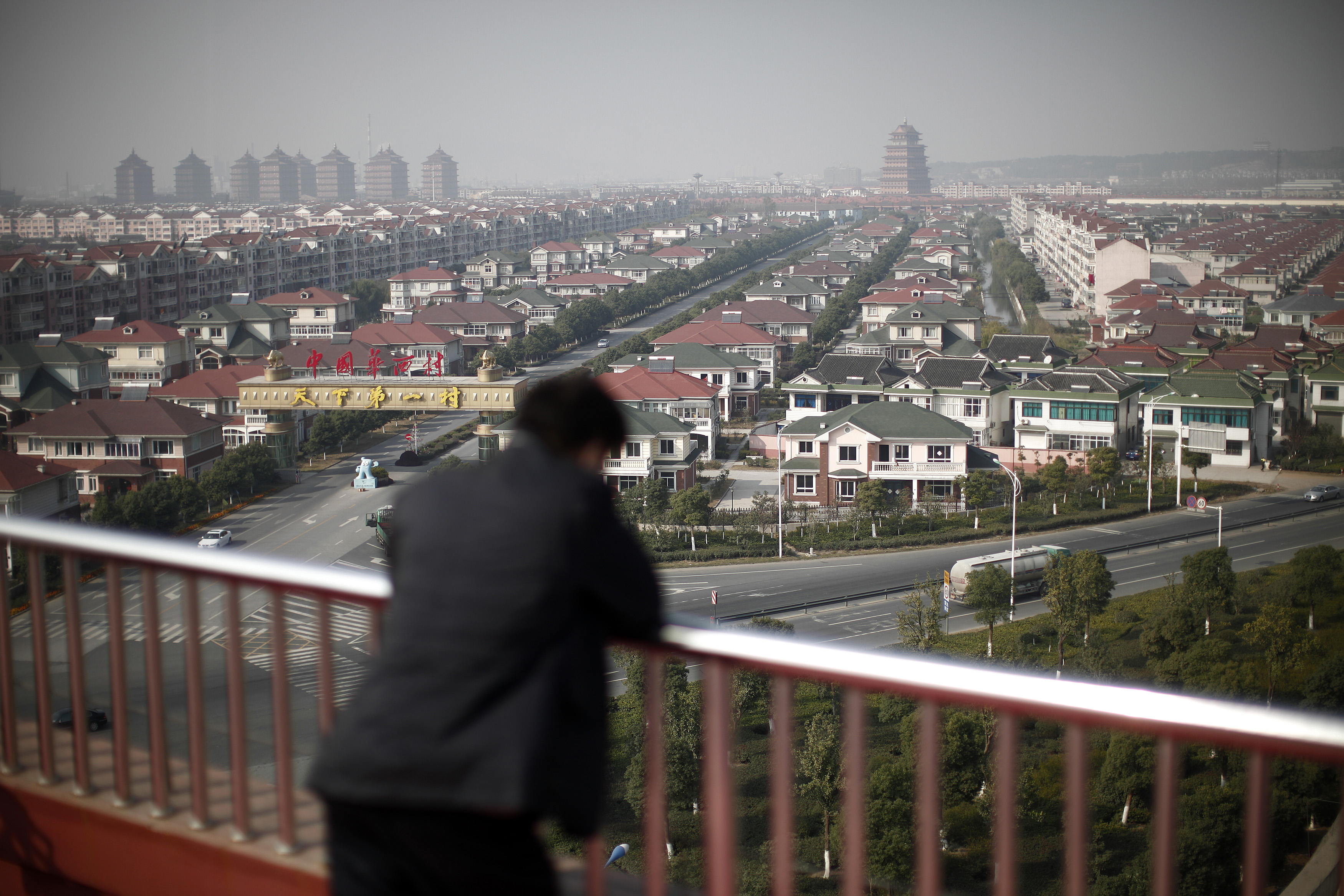 A man watches the Huaxi village, at Jiangsu province December 2, 2010. In China's richest village of Huaxi, a booming market town of 36,000 in the affluent eastern province of Jiangsu, every family has at least one house, two cars and
$250,000 in the bank. Officials from elsewhere in China tour Huaxi to find out how this once sleepy village, just 576 residents in the 1950s, is now so rich and
 why non-local businessmen would donate million-dollar factories to buy the privilege of a local residence permit. Picture taken December 2, 2010.  REUTERS/Carlos Barria  (CHINA - Tags: POLITICS BUSINESS SOCIETY) - RTXVCES