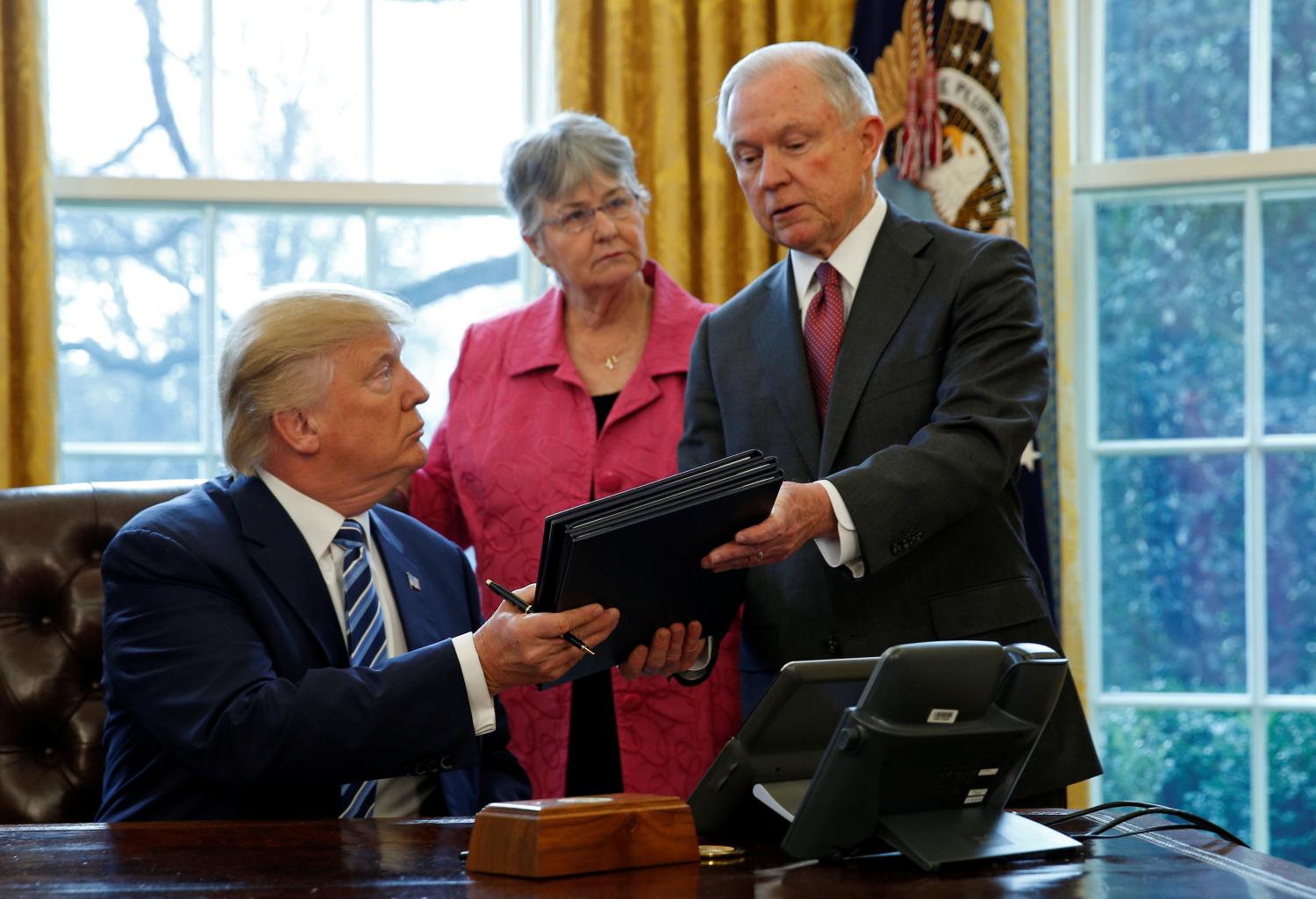 Donald Trump signs an executive order next to Jeff Sessions