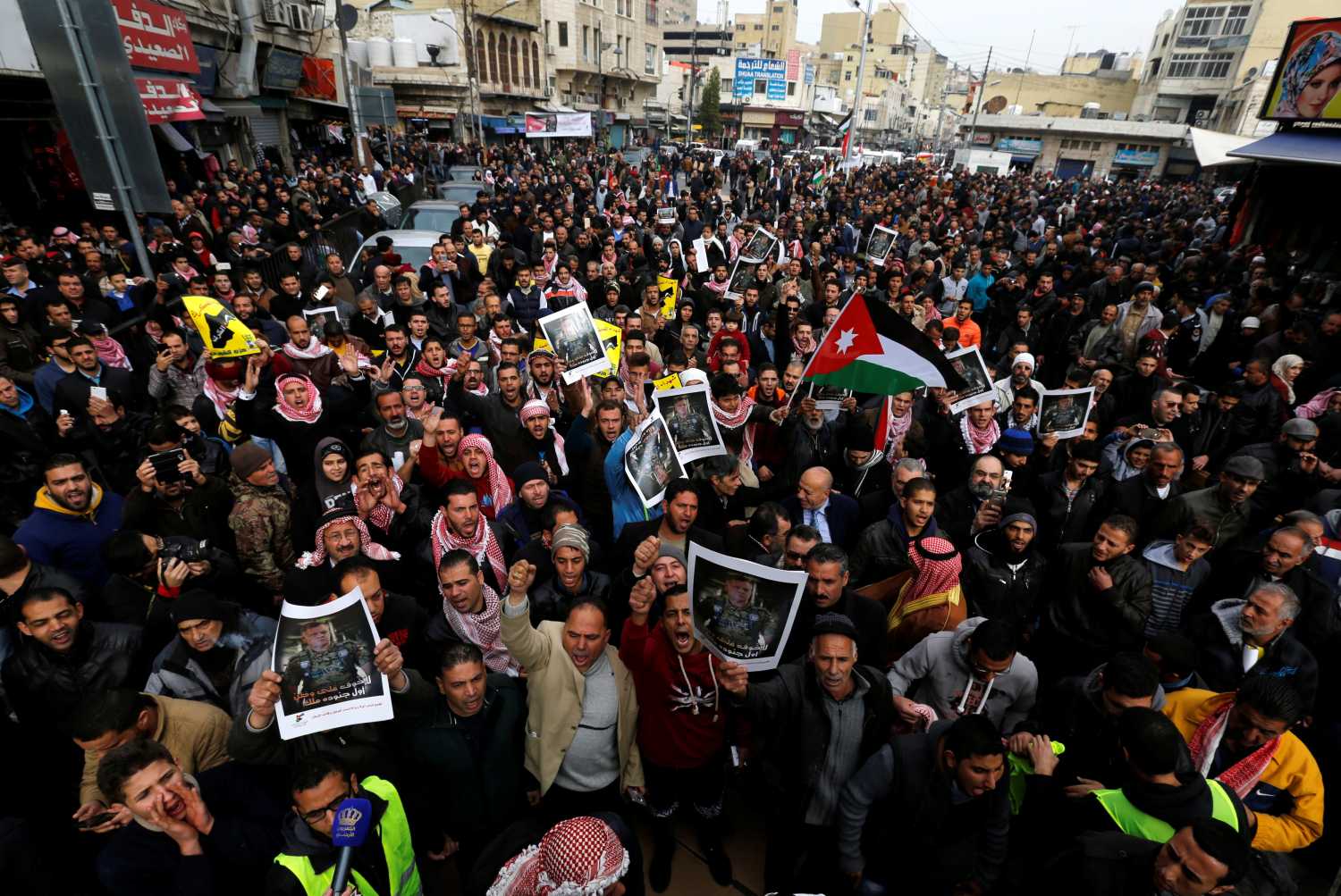 Jordanian protesters hold up pictures of Jordan's King Abdullah with national flags and chant slogans during a rally to support security services after shooting at Karak castle, in Amman, Jordan, December 23, 2016. REUTERS/Muhammad Hamed - RTX2WAJG