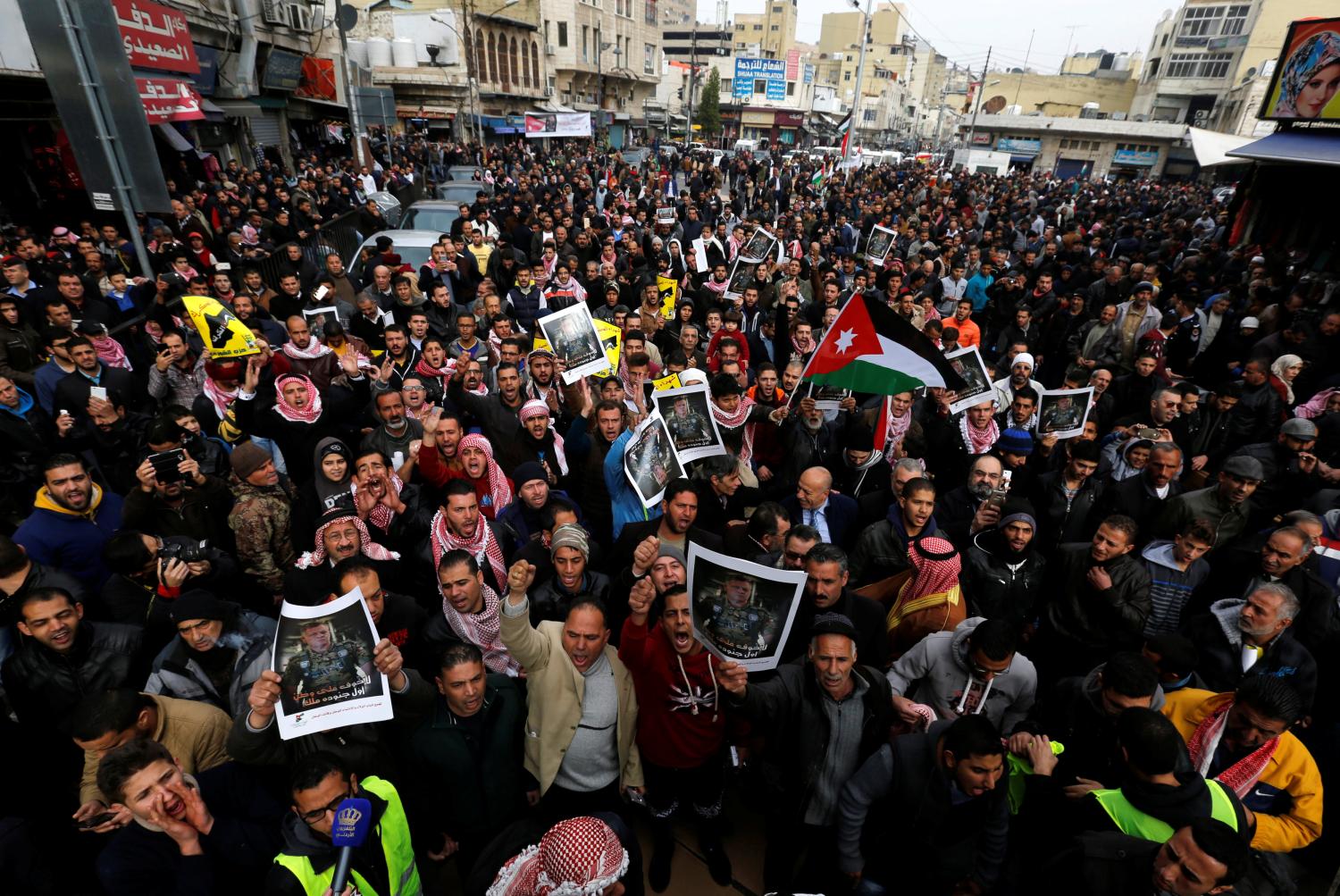 Jordanian protesters hold up pictures of Jordan's King Abdullah with national flags and chant slogans during a rally to support security services after shooting at Karak castle, in Amman, Jordan, December 23, 2016. REUTERS/Muhammad Hamed - RTX2WAJG