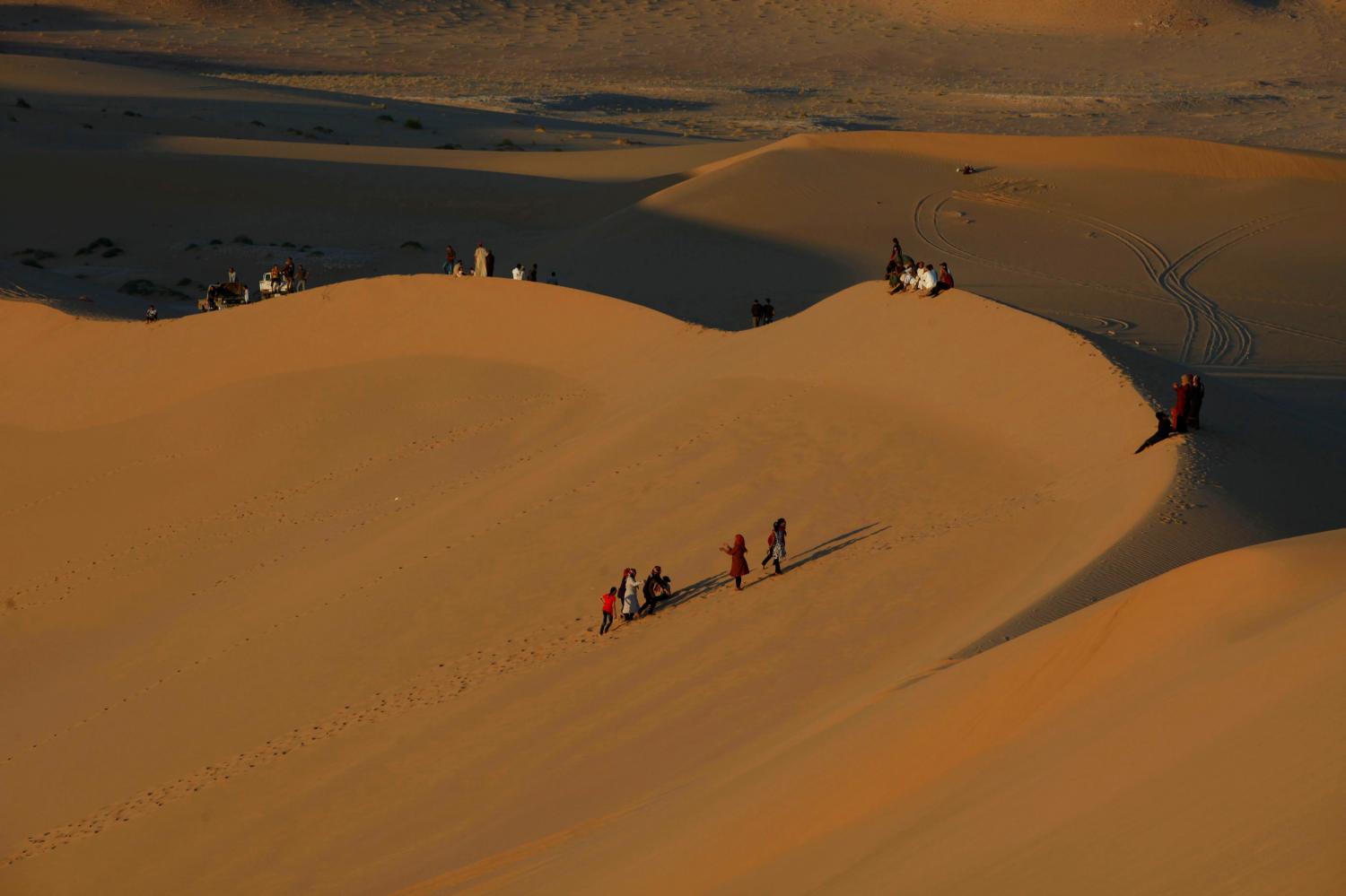 Residents walk on sand dunes in the Libyan desert oasis town of Ghadames April 19, 2013. Ghadames, a small town of around 11,000 people that lies on Libya's western border with Algeria, was a key destination for tourists who came to Libya before its Arab Spring uprising. But since the 2011 war that ousted Muammar Gaddafi, the flow of foreign holiday makers has ground to halt, as precarious security still taints Libya's image abroad. Picture taken April 19, 2013. REUTERS/Ismail Zitouny (LIBYA - Tags: POLITICS CIVIL UNREST TRAVEL SOCIETY) - RTXYVVV