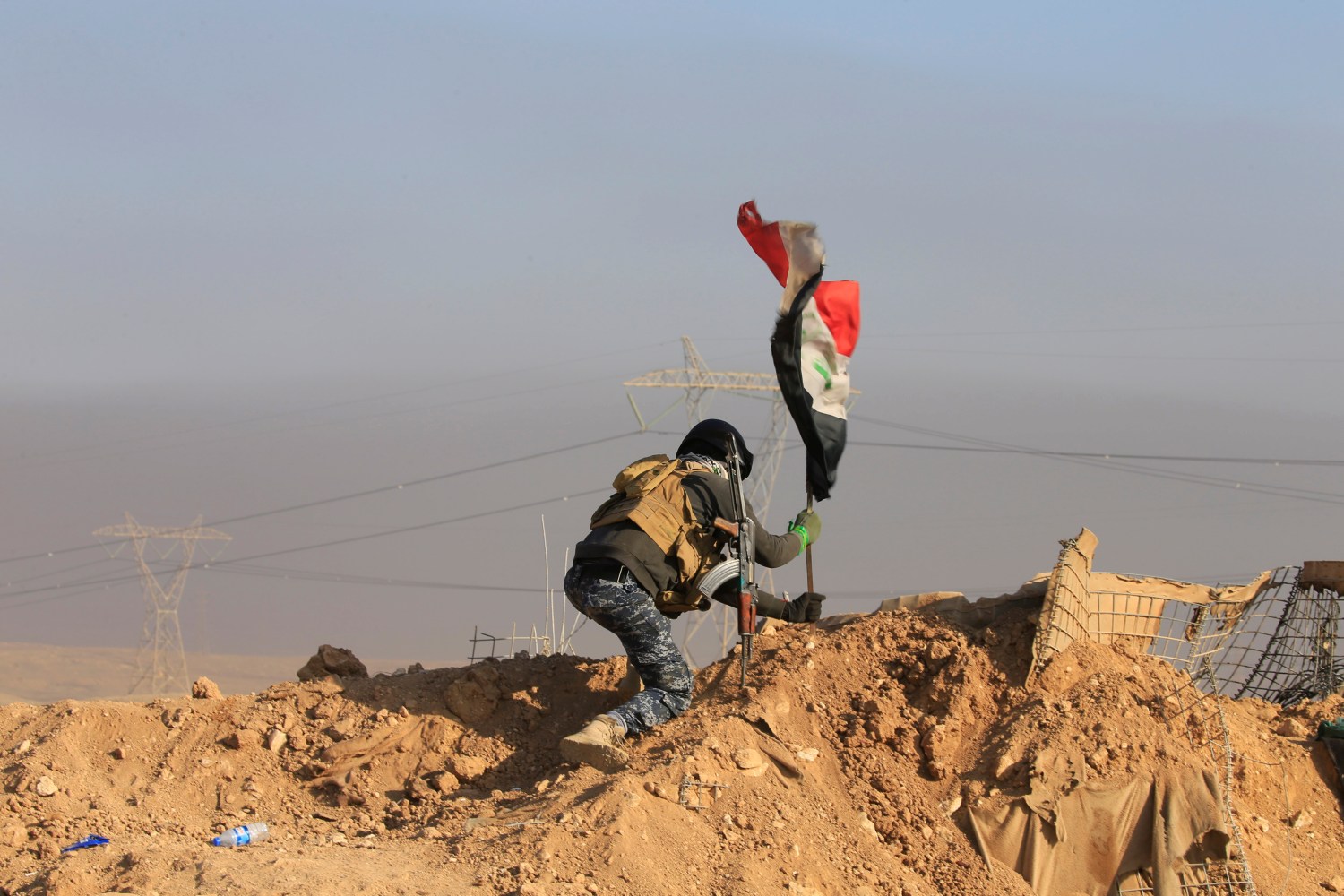 A member of the federal police forces puts up an Iraqi flag at a position during a battle with Islamic State militants in south of Mosul