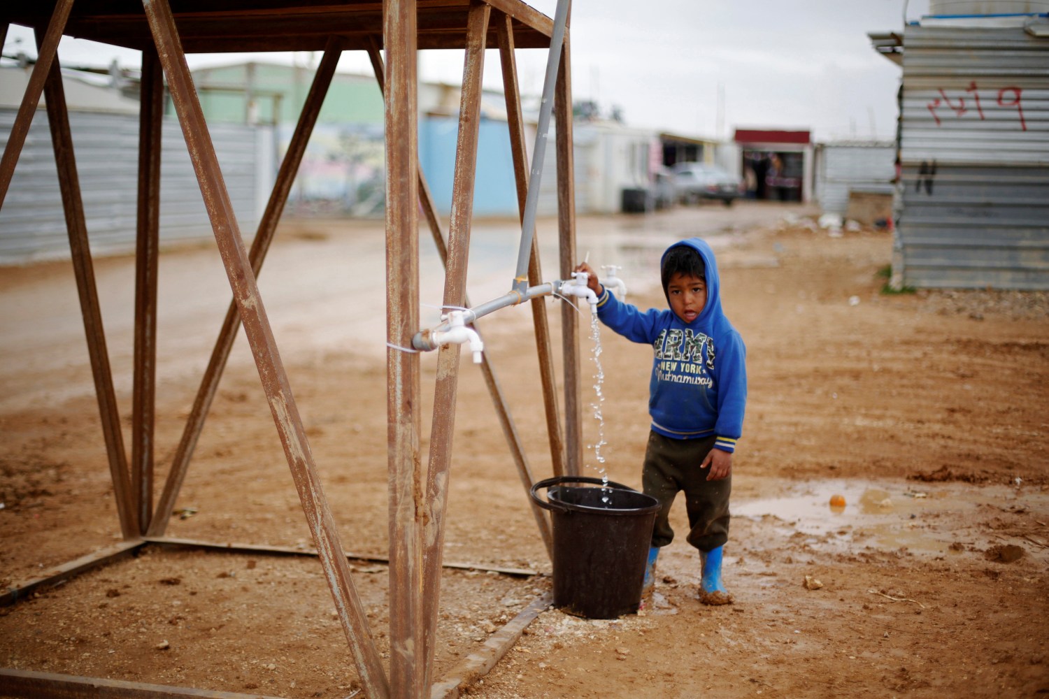 A Syrian refugee child collects water during rainy weather at the Al Zaatari refugee camp in the Jordanian city of Mafraq, near the border with Syria December 18, 2016. REUTERS/Muhammad Hamed