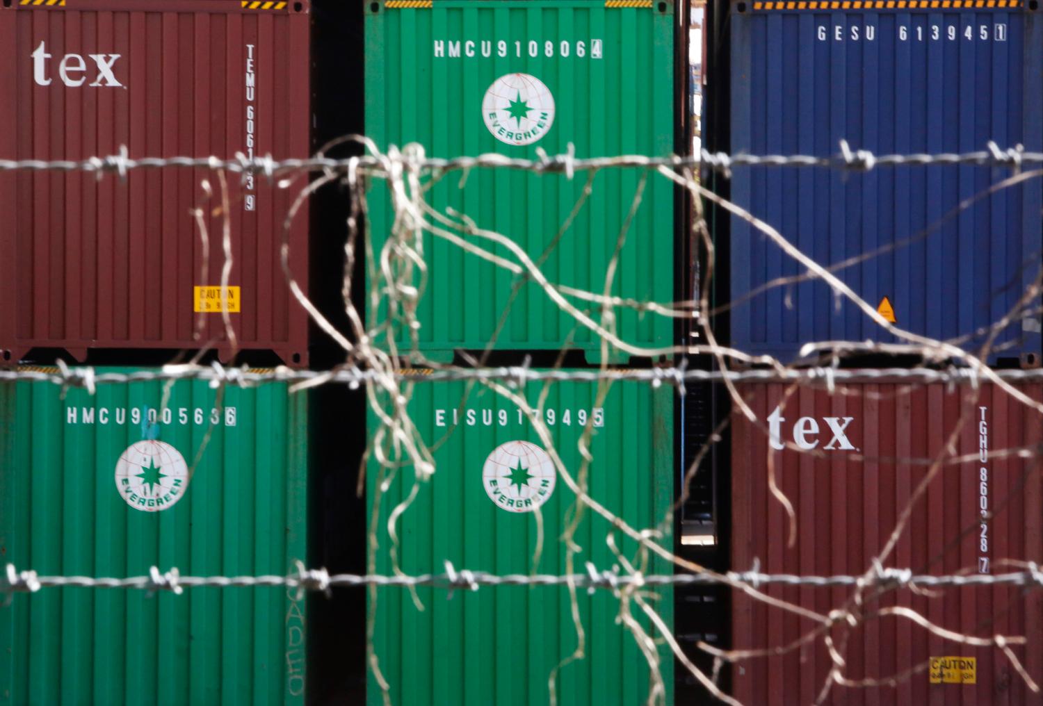 Containers are seen through a steel fence at a port in Tokyo February 20, 2013. Japan's trade deficit widened to a record in January as energy imports jumped, highlighting a risk of trying to revive the country's export engine through policies that could weaken the currency without also pursuing broader economic reforms. REUTERS/Yuya Shino