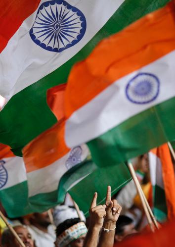 A supporter of Indian yoga guru Ramdev gestures towards Indian national flags while taking part in Ramdev's protest against corruption at the Ramlila grounds in New Delhi