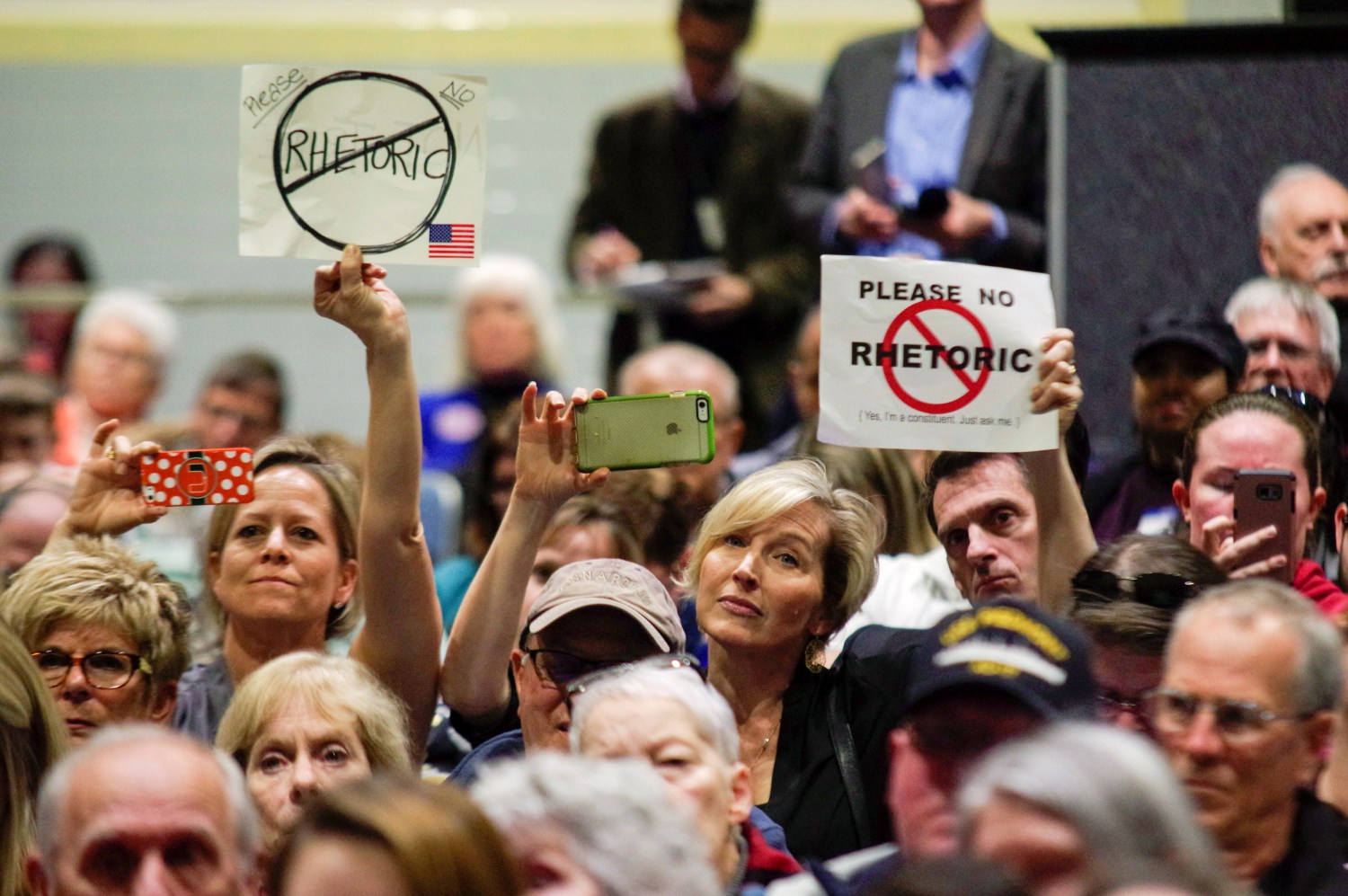 Constituents hold up signs during town hall