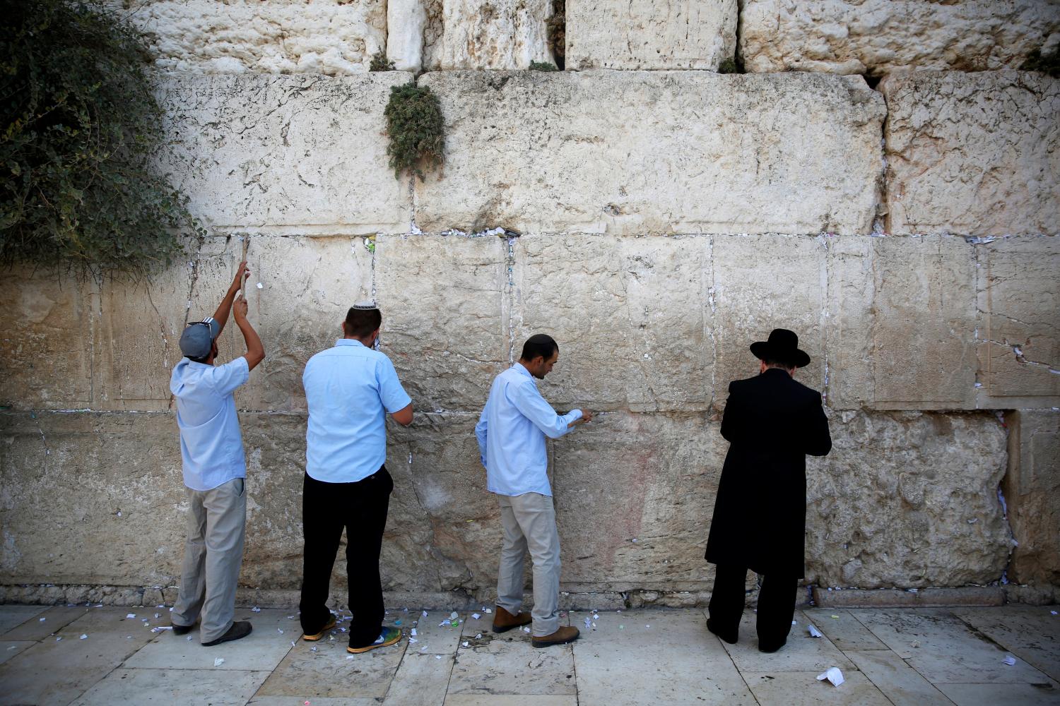 Men, including Western Wall Rabbi Shmuel Rabinowitz (R), clear notes placed in the cracks of the Western Wall, Judaism's holiest prayer site, to clear space for new notes ahead of the Jewish New Year, in Jerusalem's Old City September 27, 2016. REUTERS/Ronen Zvulun - RTSPMZT
