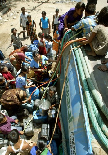 People crowd around a water tanker to fill their buckets and pots in the western Indian city of Ahmedabad May 11, 2006. At least 27 people have died in India from scorching weather, officials said on Monday. REUTERS/Amit Dave - RTR1DA14