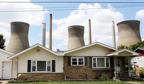 FILE PHOTO -- The John Amos coal-fired power plant is seen behind a home in Poca, West Virginia May 18, 2014. With coal production slowing due to stricter environmental controls, the availability of natural gas and a shift to surface mining, the state's coal country has been hit hard with job losses and business closures. Picture taken May 18, 2014. REUTERS/Robert Galbraith/File Photo - RTX2RU1A