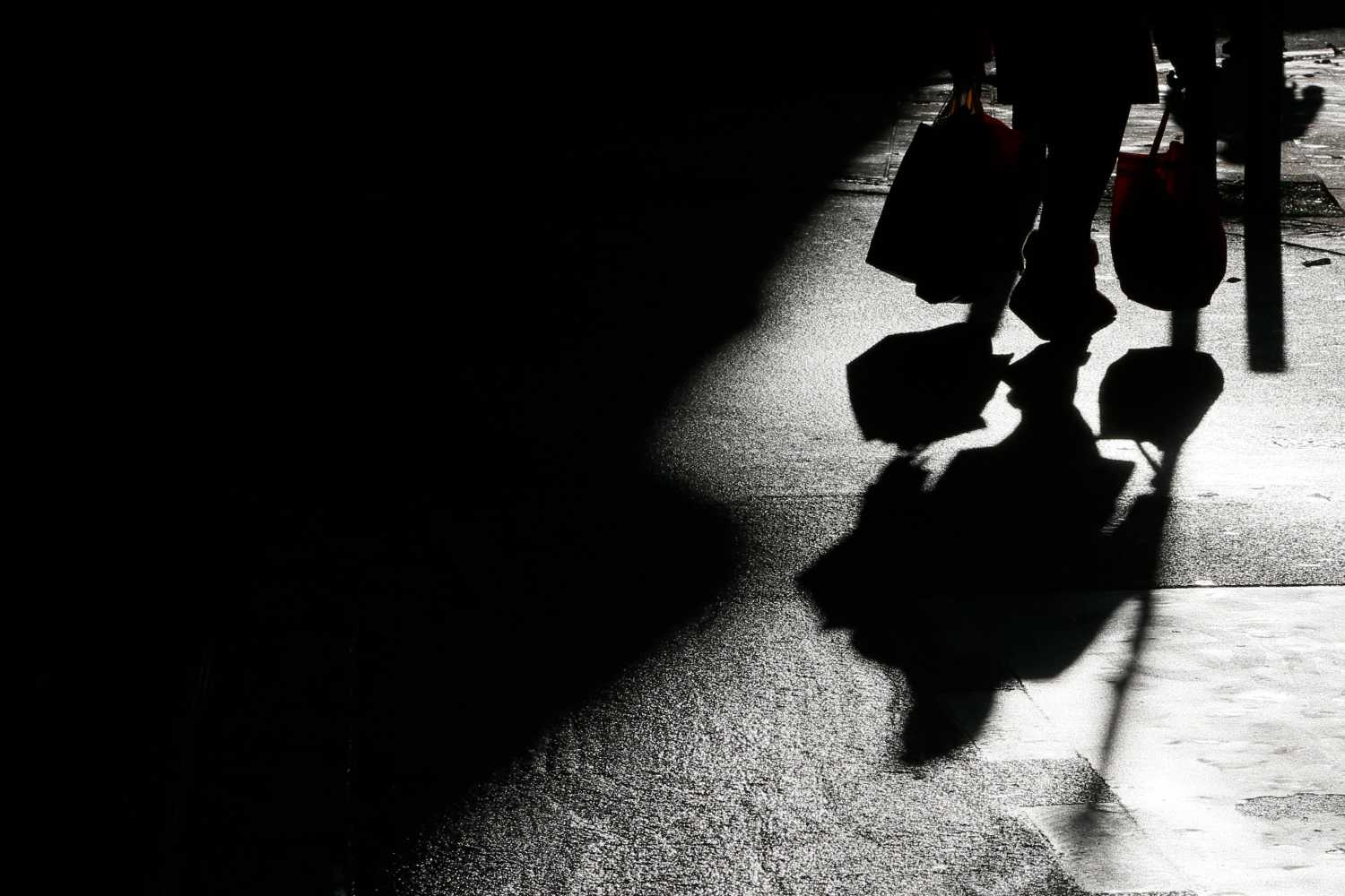 The shadow of a shopper is cast onto the ground.