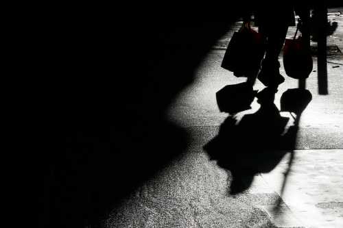 The shadow of a shopper is cast onto the ground.