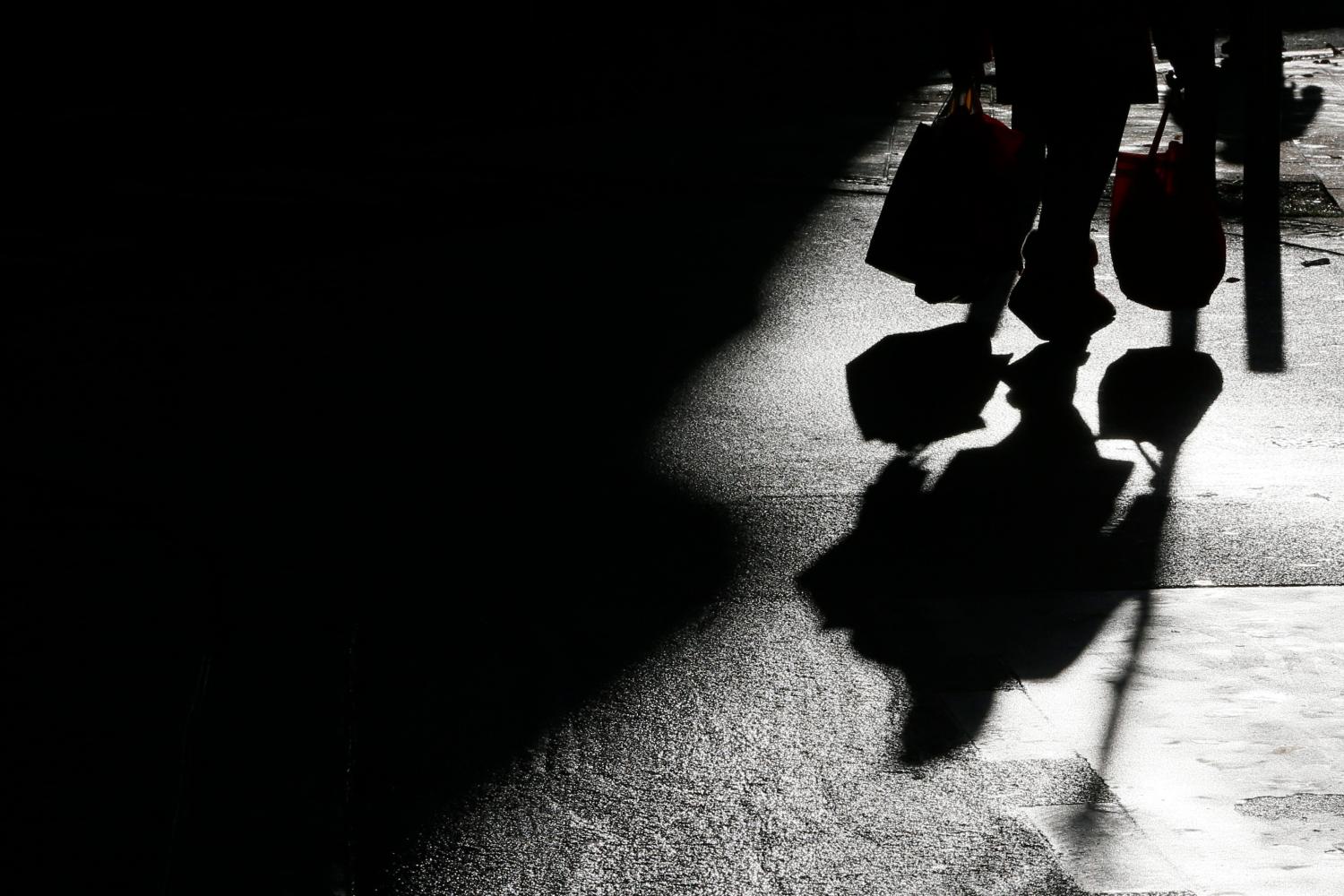 The shadow of a shopper is cast onto the ground.