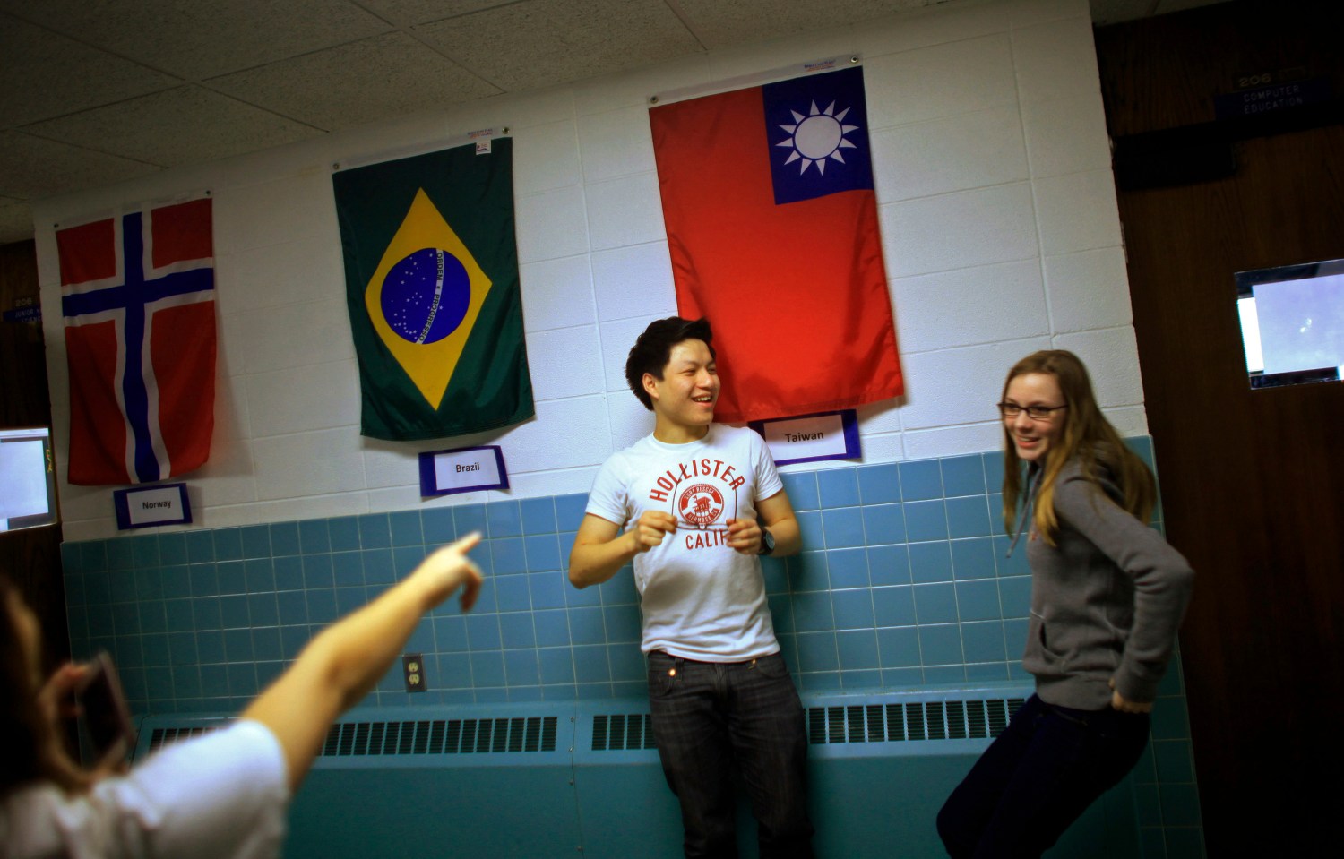 Davy Lin (C) , a foreign exchange student from Taoyuan, Taiwan and Lena Kraft, from Munich, Germany joke around in the hallways at Grant-Deuel School in Revillo, South Dakota February 13, 2012. This year, 11 students from China, Thailand, Germany and elsewhere account for nearly 20% of high school enrollment, bringing cash and a welcome splash of diversity to an isolated patch of the Great Plains. Grant-Deuel is not alone. Across the United States, public high schools in struggling small towns are putting their empty classroom seats up for sale. Picture taken February 13. To match Insight USA-SCHOOLS/FOREIGN REUTERS/Jim Young (UNITED STATES - Tags: EDUCATION SOCIETY) - RTR2Z0KK